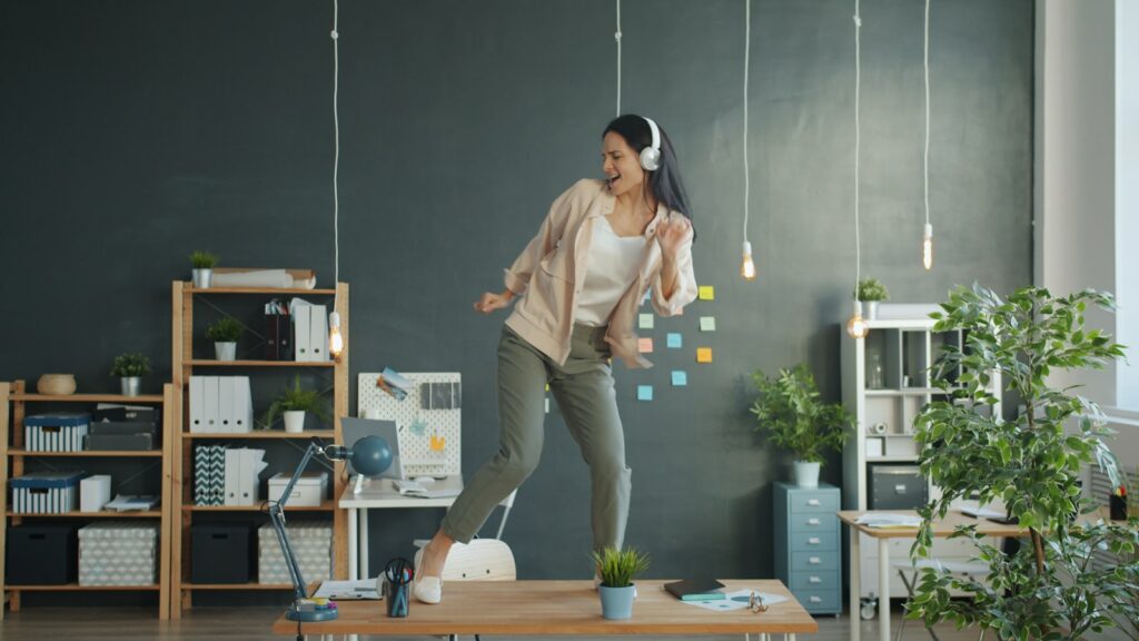 Woman dancing on desk with headphones on