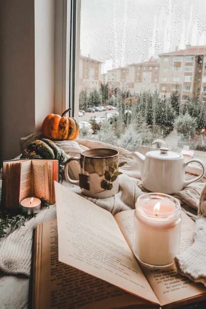 a table with a book and coffee cups on it with a window in the background