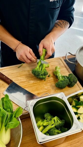 a person cutting broccoli on a cutting board