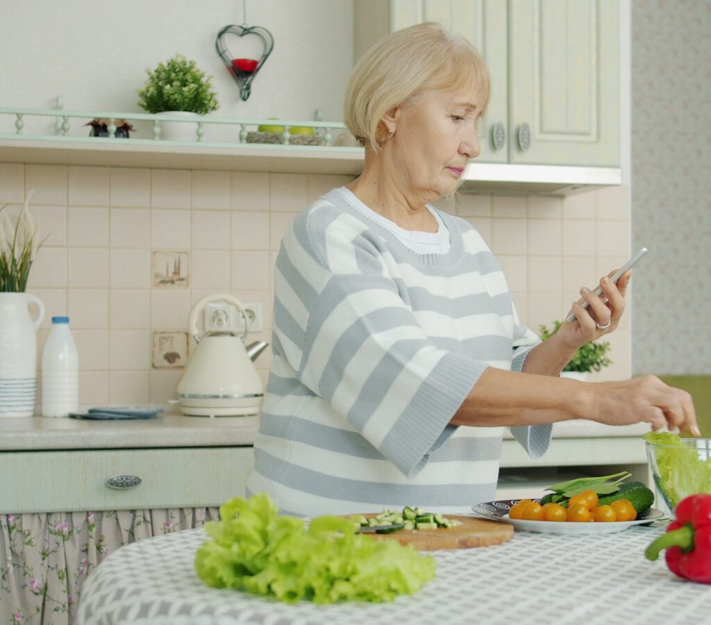 Elderly woman preparing salad in a kitchen