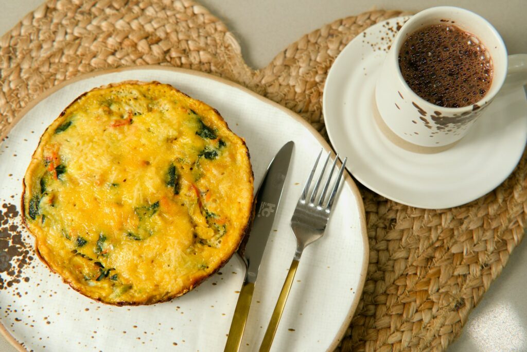a white plate topped with a quiche next to a cup of coffee