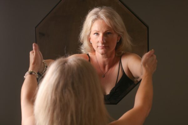 A woman standing in front of a mirror brushing her hair