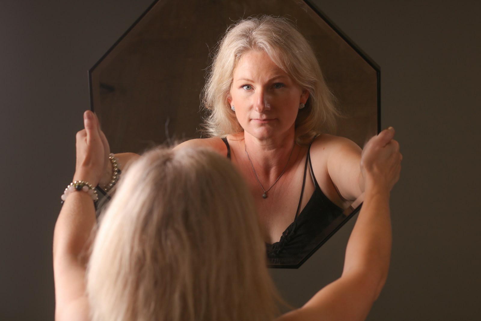 A woman standing in front of a mirror brushing her hair