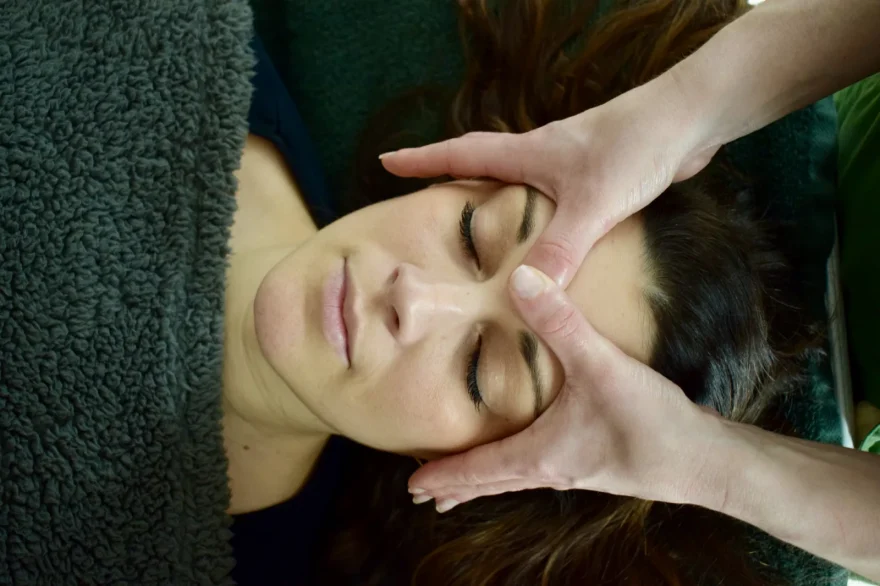 Massage du visage, mains de la praticienne sur le front d'une cliente