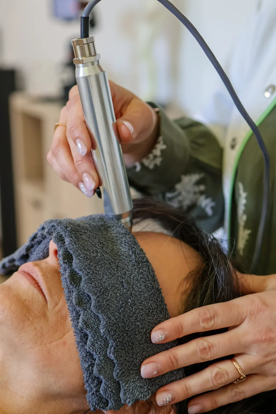 Stylet infrarouge posé sur le front d'une cliente, un linge sur les yeux