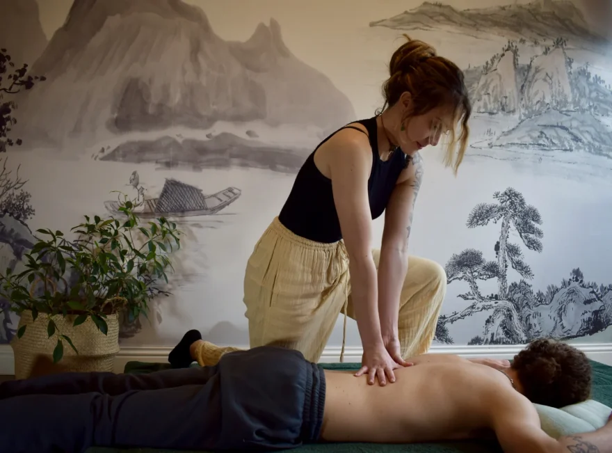 Praticienne pressant le dos d'une personne allongée sur un futon, pendant un shiatsu