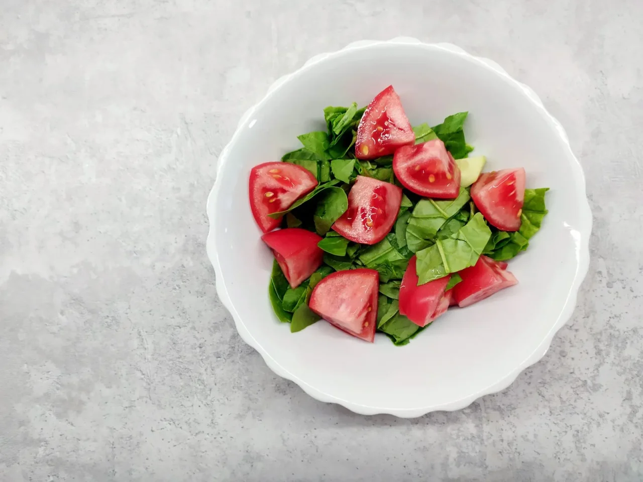 Une salade d'épinards et de tomates dans un bol en céramique