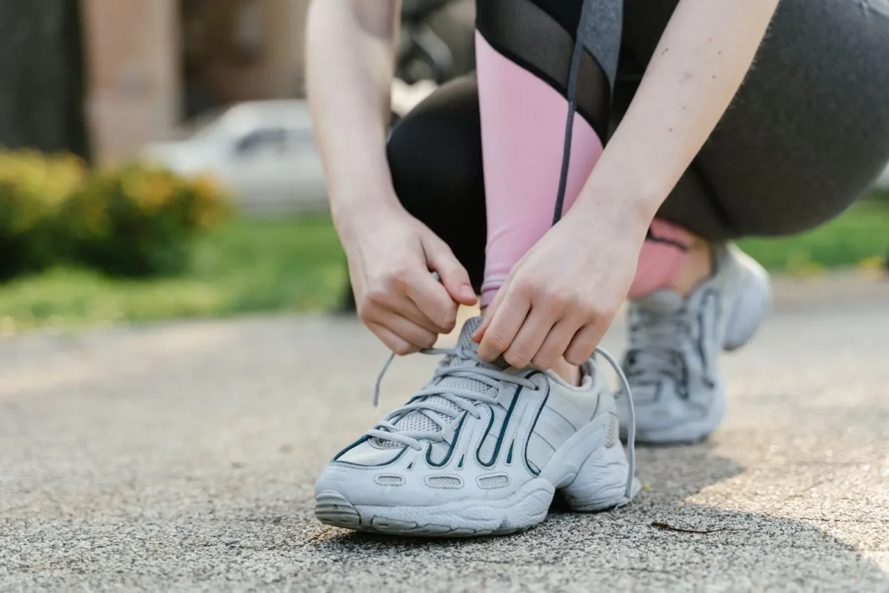 Une femme lace ses baskets avant de partir marcher
