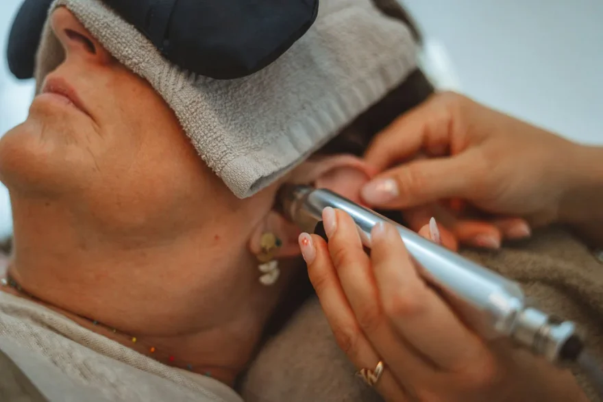 Séance de luxopuncture à l’oreille, une cliente allongée avec un masque de repos sur les yeux