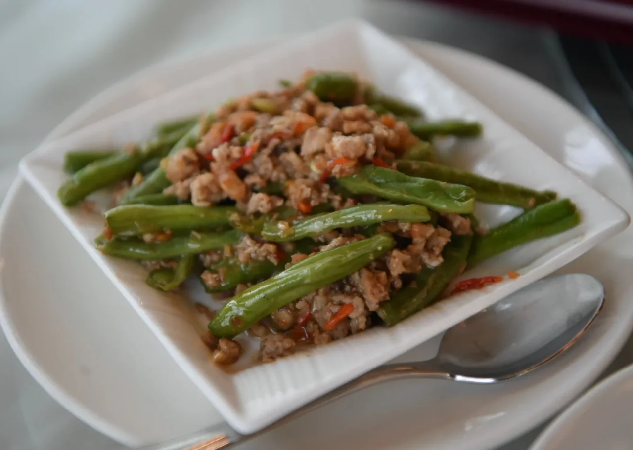 De la viande hachée et des haricots verts sautés dans une assiette carrée blanche